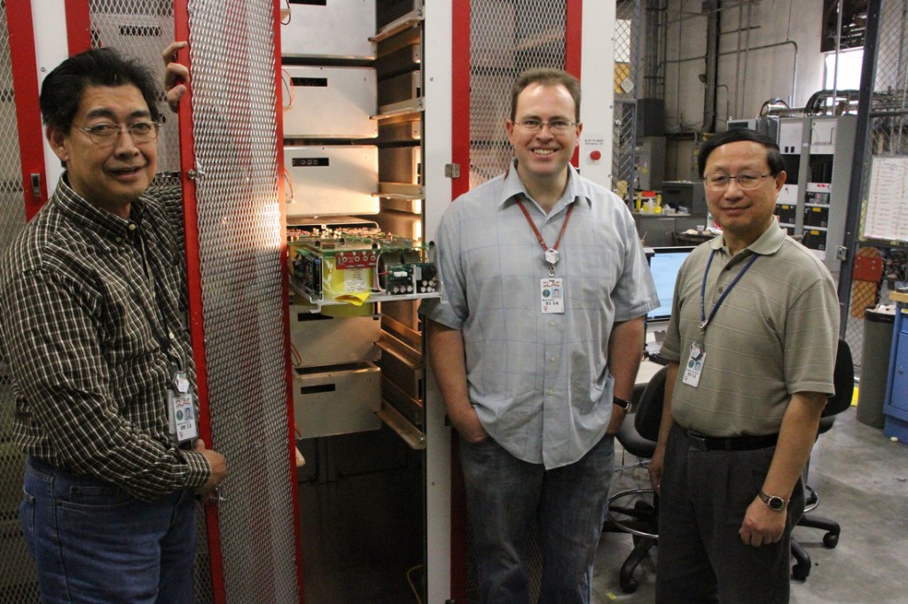 Alfred Viceral, Mark Kemp and Patrick Shen, who worked on the development of the Marx P2, stand in front of the enclosed modulator. One cell is pulled out of its drawer. Image: Ray Larsen